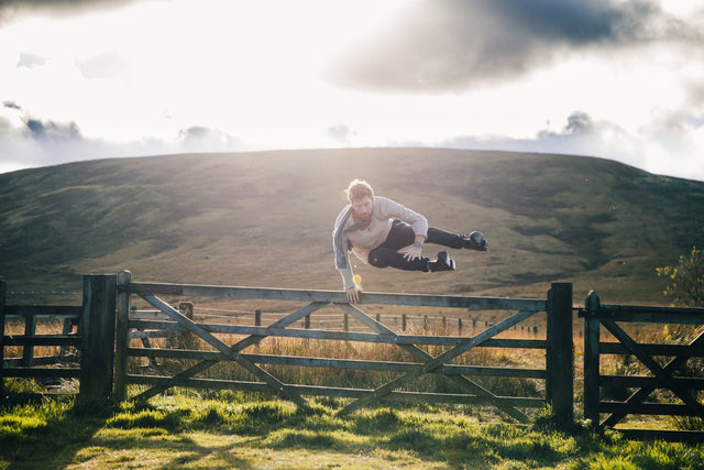 man jumping over fence carrying nothing